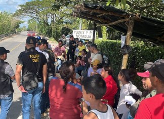 Agentes policiales y de Migración dialogan con un grupo de migrantes que recién cruzaron la frontera entre Honduras y Guatemala. Foto / IGM: