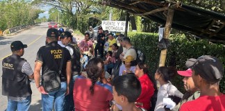 Agentes policiales y de Migración dialogan con un grupo de migrantes que recién cruzaron la frontera entre Honduras y Guatemala. Foto / IGM: