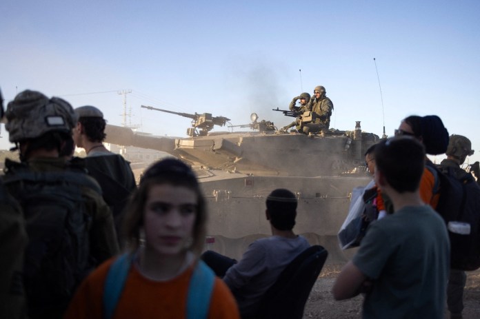 Un tanque de batalla israelí pasa junto a activistas de derecha cerca del cruce de Erez mientras se manifiestan pidiendo la construcción de asentamientos israelíes en Gaza, el 29 de febrero de 2024, en medio de las batallas en curso entre Israel y el grupo militante palestino Hamas. (Foto de Oren ZIV / AFP)