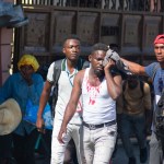 Un periodista herido recibe ayuda después de que, según informes, fue alcanzado por un bote de gas lacrimógeno disparado por la policía en Puerto Príncipe, Haití, el 9 de marzo de 2024. Foto: AFP.