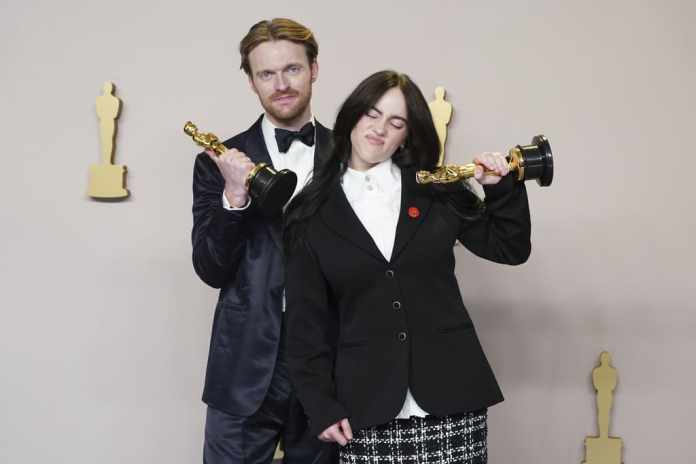 Finneas O'Connell y Billie Eilish posan en la sala de prensa con su Oscar por mejor canción original por 