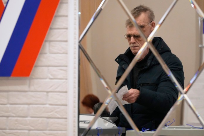 Un hombre se ve reflejado en un espejo mientras vota en un centro electoral durante las elecciones presidenciales rusas, el sábado 16 de marzo de 2024, en San Petersburgo, Rusia. (AP Foto/Dmitri Lovetsky)