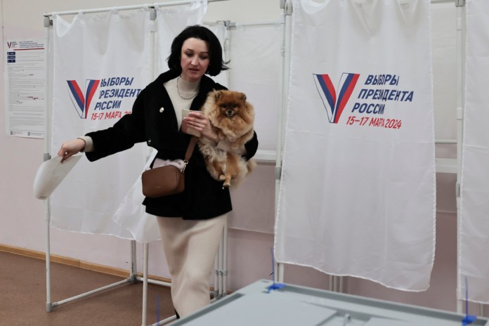 Una mujer sostiene su mascota a su salida de una cabina electoral durante las elecciones presidenciales el domingo 17 de marzo de 2024, en la ciudad portuaria de Vladivostok, en el oriente de Rusia. (AP Foto)