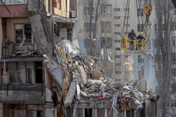 Rescuers clear debris from a multi-story building heavily damaged following a drone strike, in Odesa on March 3, 2024, amid the Russian invasion of Ukraine. Two more bodies have been found following a deadly Russian drone strike on the southern port city of Odesa, Ukraine said on March 3, 2024. The deaths of a woman and her eight-month-old baby take the toll to ten from the strike overnight between March 1, 2024 and March 2, 2024. (Photo by Oleksandr GIMANOV and Oleksandr GIMANOV / AFP)