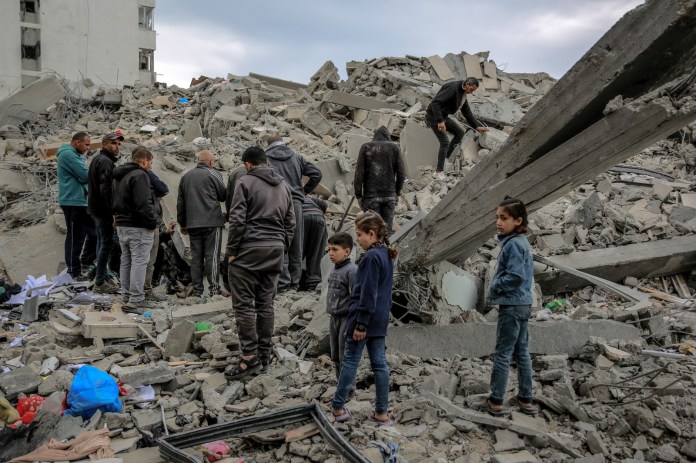 Los palestinos inspeccionan los escombros de un edificio, después de que fuera destruido en un ataque israelí la noche anterior, en el barrio Rimal de la ciudad de Gaza el 16 de marzo de 2024, en medio de batallas en curso entre Israel y el movimiento palestino Hamas. (Foto de AFP)