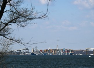 Una grúa comienza la limpieza en el puente Francis Scott Key colapsado después de que fuera golpeado por el buque portacontenedores Dali, en Baltimore, Maryland, el 29 de marzo de 2024. Las grúas comenzaron a llegar el 28 de marzo al lugar del catastrófico colapso del puente sobre el puerto de Baltimore. , mientras las autoridades pasaron a una fase de limpieza de la recuperación y advirtieron sobre un trabajo extenso antes de que el principal puerto estadounidense pueda reabrir. Se cree que cuatro hombres, todos inmigrantes latinoamericanos, murieron cuando el buque portacontenedores con bandera de Singapur perdió potencia y chocó contra una columna de soporte del puente. (Foto de Mandel NGAN / AFP)