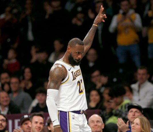 El alero de los Lakers de Los Ánngeles LeBron James recibe el reconocimiento de la fanaticada mientras se dirige al banquillo en los instantes finales del último período del juego de baloncesto ante los Nets de Brooklyn, el domingo 31 de marzo de 2024, en Nueva York. (AP Foto/John Munson)