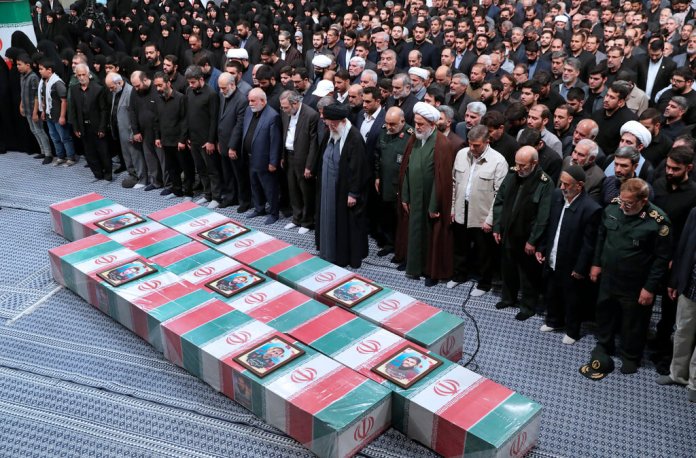 El ayatolá Ali Jamenei encabeza una oración junto a los ataúdes, envueltos en banderas nacionales, de los miembros de la Guardia Revolucionaria que murieron en un ataque aéreo en Siria. (Oficina del líder supremo de Irán vía AP)