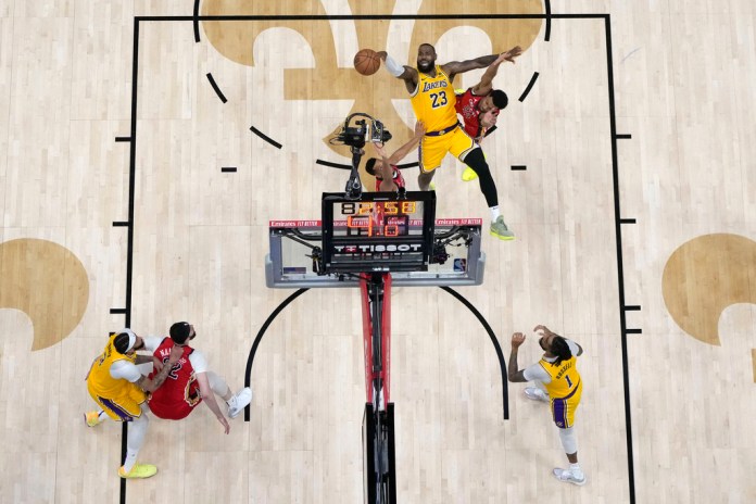 LeBron James (23), dispara entre el base de los New Orleans Pelicans, Trey Murphy III, y el base CJ McCollum en la segunda mitad de un partido del torneo de baloncesto de la NBA el martes 16 de abril de 2024 en Nueva Orleans. Los Lakers ganaron 110-106. (Foto AP/Gerald Herbert)