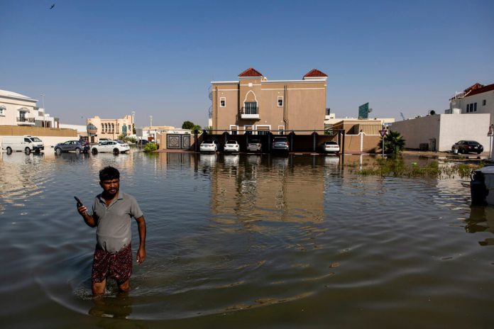 Un hombre camina entre las inundaciones causadas por las fuertes lluvias en Dubai. (Foto AP/Christopher Pike)