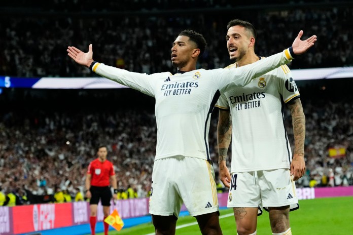 Jude Bellingham, izquierda, del Real Madrid, celebra con Joselu tras anotar el tercer gol de su equipo durante el partido de fútbol de la Liga española entre Real Madrid y Barcelona en el estadio Santiago Bernabeu de Madrid, España, el domingo 21 de abril de 2024. (Foto AP/José bretón)