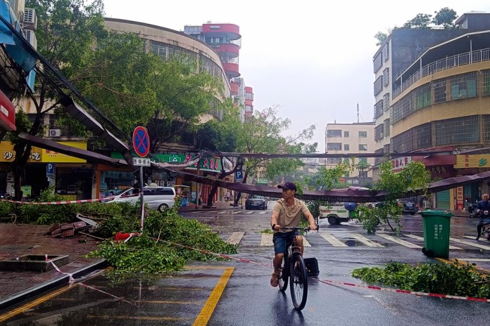Un ciclista pasa entre escombros y árboles caídos después de fuertes tormentas en la ciudad de Qingyuan, en el sur de China, el lunes 22 de abril de 2024. (Chinatopix vía AP)