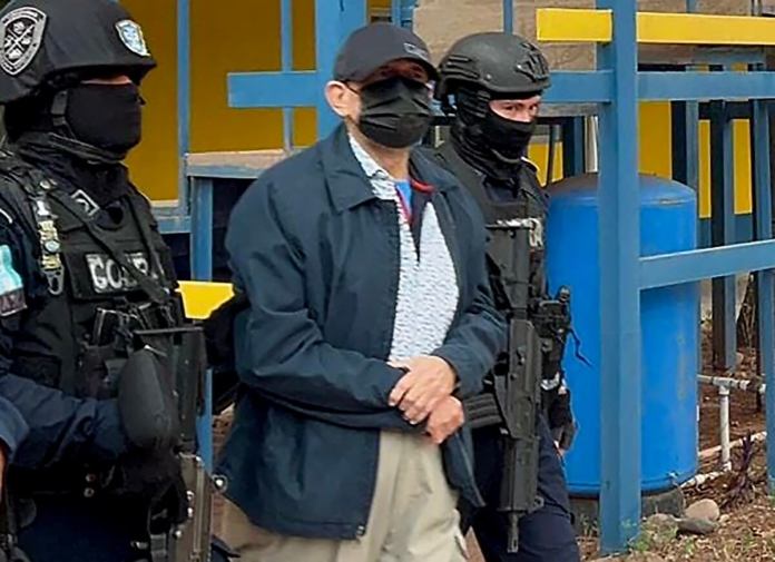 Miembros de las Fuerzas Especiales de la Policía Nacional escoltan a Francisco Roberto Cosenza, mientras es trasladado de la Dirección de Fuerzas Especiales para ser extraditado a Estados Unidos. (Foto por Folleto / POLICÍA HONDURAS / AFP)