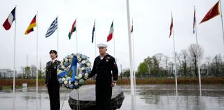 Dos militares se ven bajo las banderas de los estados miembros de la OTAN durante una ofrenda floral en la sede de la alianza en Bruselas, el jueves 4 de abril de 2024. La OTAN celebra el jueves 75 años desde la firma de su tratado fundacional. (AP Foto/Virginia Mayo)