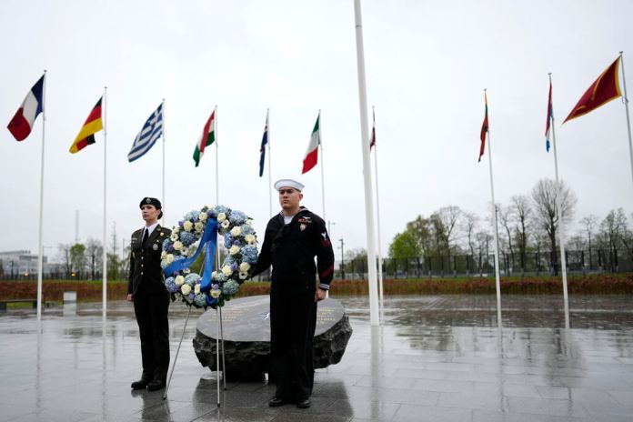 Dos militares se ven bajo las banderas de los estados miembros de la OTAN durante una ofrenda floral en la sede de la alianza en Bruselas, el jueves 4 de abril de 2024. La OTAN celebra el jueves 75 años desde la firma de su tratado fundacional. (AP Foto/Virginia Mayo)