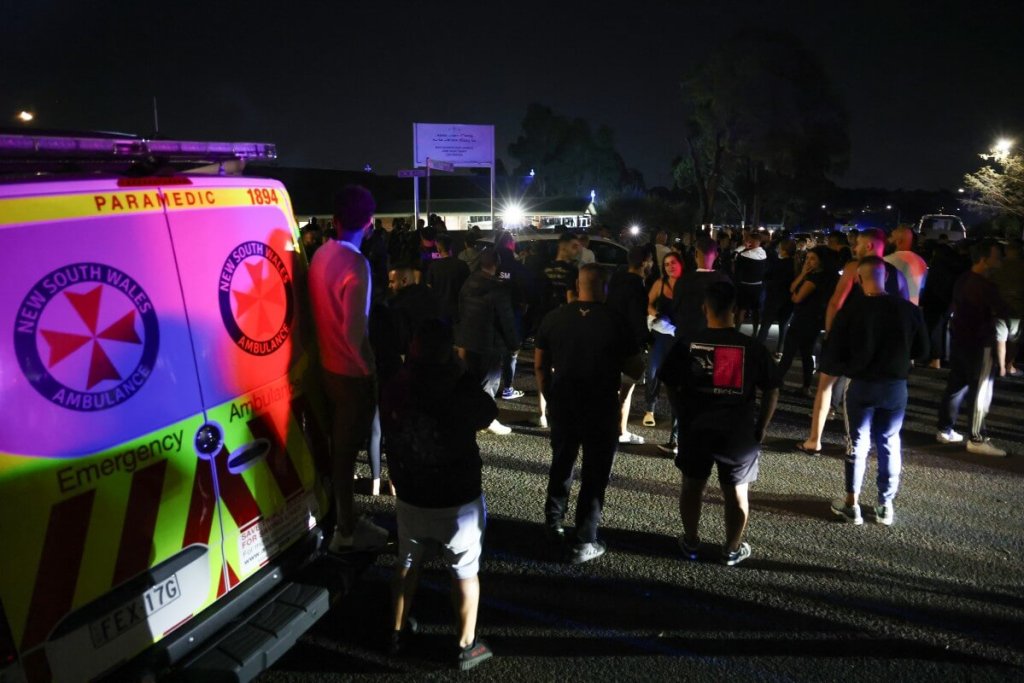 Los lugareños se reúnen con la policía para proteger el perímetro de la Iglesia de Cristo el Buen Pastor en el suburbio de Wakeley, al oeste de Sydney, el 15 de abril de 2024, después de que varias personas fueran apuñaladas en las instalaciones de la iglesia. (Foto de DAVID GRAY / AFP)