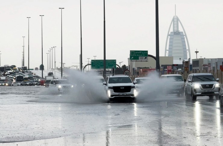 Una camioneta arroja agua a su paso por una carretera anegada, con el edificio Burj Al Arab, de fondo, en Dubái, Emiratos Árabes Unidos, el 16 de abril de 2024. (AP Foto/Jon Gambrell)