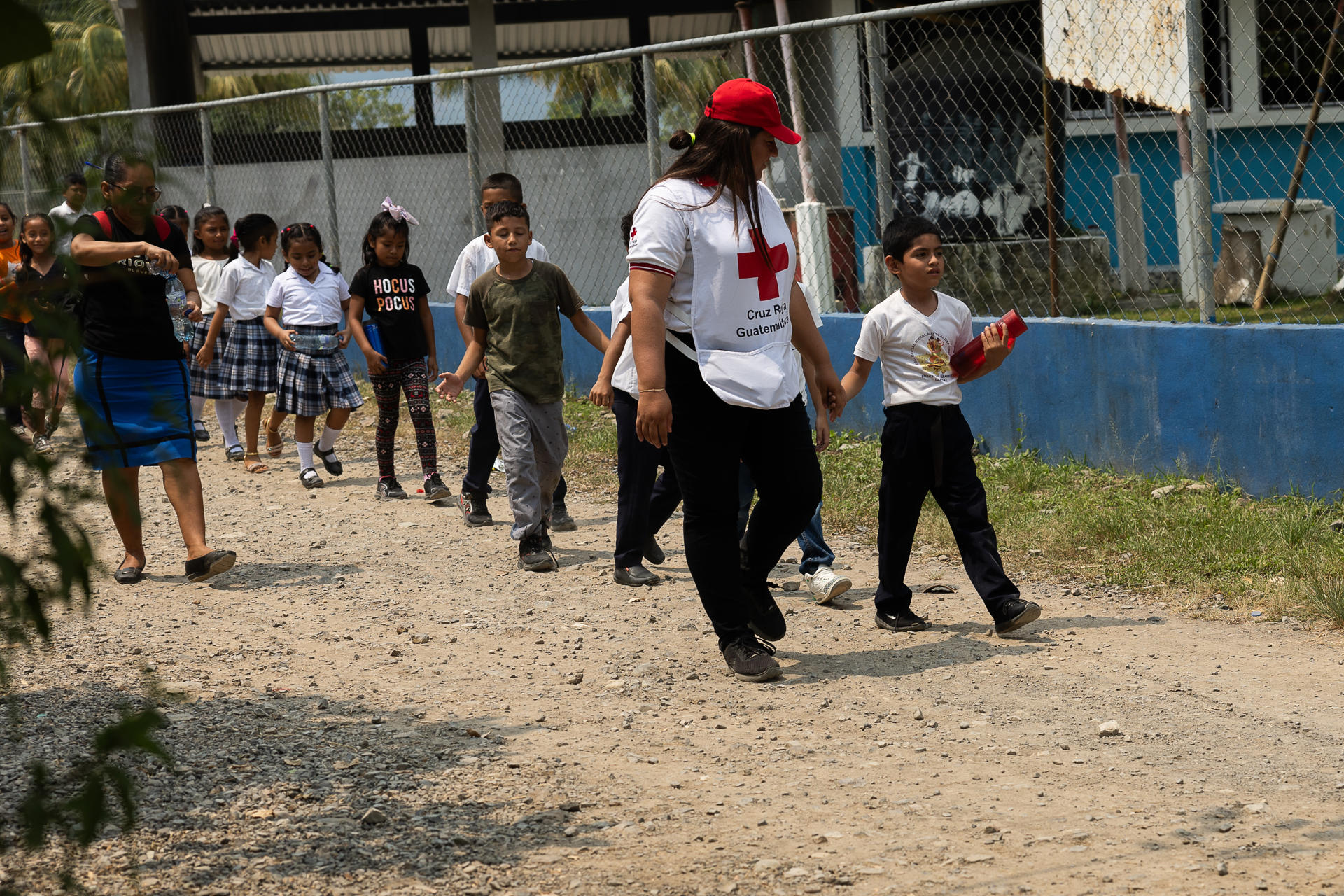 GUA3001. Izabal (GUATEMALA).14/05/2024.- Estudiantes de la escuela primaria de la aldea Jimerios, en el extremo noroeste de Guatemala, a pocos kilómetros de la frontera con Honduras, caminaban el pasado 2 de mayo con personal de la Cruz Roja guatemalteca hacia una charla sobre prevención del dengue. Esta región de Guatemala es una de las más afectadas por la epidemia de dengue de los últimos tres años . EFE/David Toro