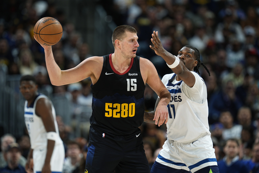 El centro de los Denver Nuggets, Nikola Jokic, izquierda, busca pasar el balón mientras el centro de los Minnesota Timberwolves, Naz Reid, defiende durante la segunda mitad del Juego 2 de una serie de playoffs de segunda ronda de baloncesto de la NBA, el lunes 6 de mayo de 2024, en Denver. (Foto AP/David Zalubowski)