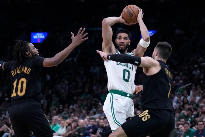 El delantero de los Boston Celtics, Jayson Tatum (0), busca pasar mientras está cubierto por Max Strus, de los Cleveland Cavaliers, derecha, y Darius Garland (10) durante la primera mitad del Juego 1 de una serie de playoffs de segunda ronda de baloncesto de la NBA el martes 7 de mayo de 2024. , en Boston. (Foto AP/Charles Krupa)