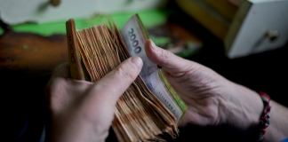 Un trabajador cuenta el dinero en una tienda de abarrotes en Buenos Aires, Argentina, 21 de noviembre de 2023. (AP Foto/Natacha Pisarenko, Archivo)