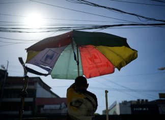 Un vendedor ambulante prepara su sombrilla. (AP Foto/Aaron Favila, Archivo)