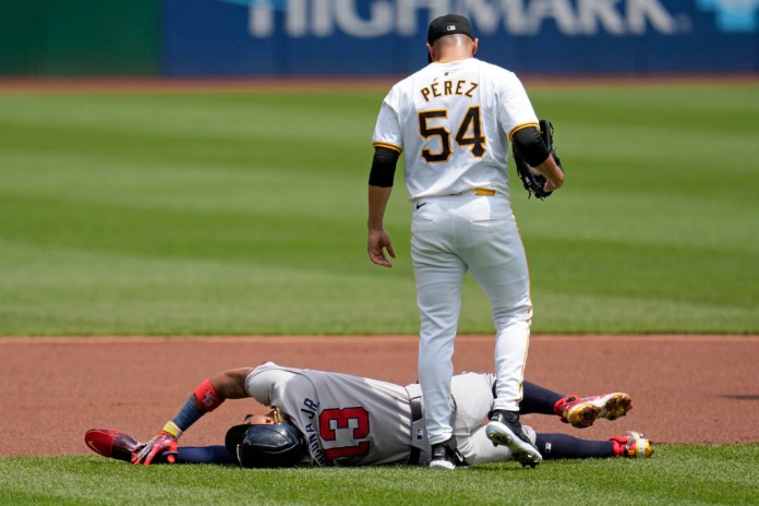 El lanzador de los Piratas de Pittsburgh, Martín Pérez (54), observa a Ronald Acuña Jr., de los Bravos de Atlanta, quien se lesionó en un intento de robo de tercera base durante la primera entrada del juego de béisbol del domingo 26 de mayo de 2024. Acuña Jr. abandonó el juego. (AP Foto/Gene J. Puskar)