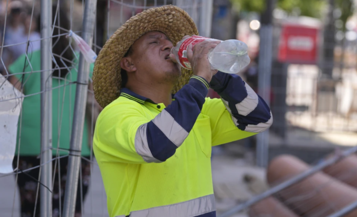 Un trabajador de carreteras hace un descanso para beber agua. (AP Foto/Paul White, Archivo)