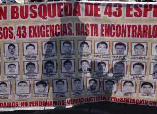 ARCHIVO - Familiares y amigos de los 43 estudiantes de Ayotzinapa desaparecidos marchan con un cartel con las fotos y el nombre de los jóvenes en el noveno aniversario de su desaparición, en Ciudad de México, el 26 de septiembre de 2023. Una corte federal mexicana decidió el jueves 9 de mayo de 2024 que ocho de los militares acusados en el caso Ayotzinapa sigan el proceso en libertad. (AP Foto/Marco Ugarte, Archivo)
