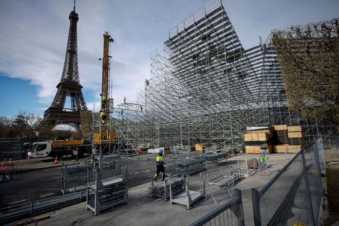 Trabajadores construyen gradas para los venideros Juegos Olímpicos en el Campo de Marte, justo al lado de la Torre Eiffel, en París, el 1 de abril de 2024. (AP Foto/Thomas Padilla)