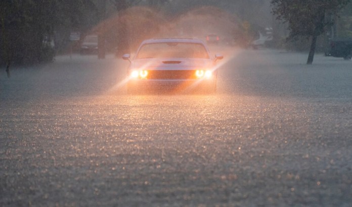 Un conductor parpadea sus luces de emergencia mientras cae una fuerte lluvia sobre partes del sur de Florida. (Matias J. Ocner/Miami Herald via AP)