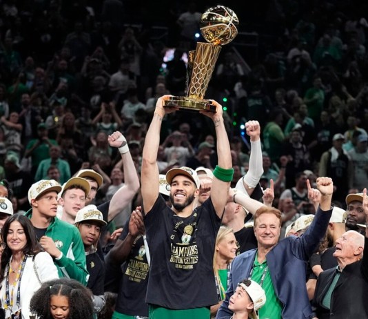 El delantero de los Boston Celtics, Jayson Tatum, sostiene, en el centro, el Trofeo del Campeonato Larry O'Brien mientras celebra con el equipo después de que ganaron el campeonato de baloncesto de la NBA con una victoria en el Juego 5 sobre los Dallas Mavericks, el lunes 17 de junio de 2024, en Boston. (Foto AP/Charles Krupa)
