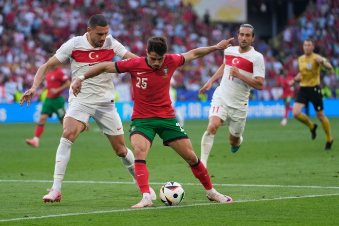 El portugués Pedro Neto, en el centro, disputa el balón con el turco Merih Demiral, a la izquierda, durante un partido del Grupo F entre Turquía y Portugal en el torneo de fútbol Euro 2024 en Dortmund, Alemania, el sábado 22 de junio de 2024. (Foto AP/Darko Vojinovic )