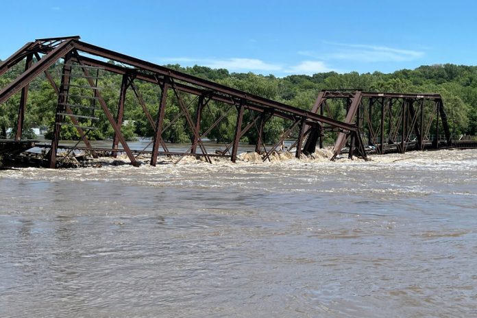 Un puente ferroviario que vincula a North Sioux City, Dakota del Sur, con Sioux City, Iowa, yace parcialmente sobre el río Big Sioux el lunes 24 de junio de 2024 debido a inundaciones. (AP Foto/Margery A. Beck)