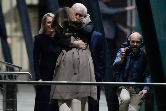 Julian Assange, fundador de WikiLeaks, abraza a su esposa Stella tras aterrizar en la base de las Fuerzas Armadas Australianas. (AP Foto/Rick Rycroft)