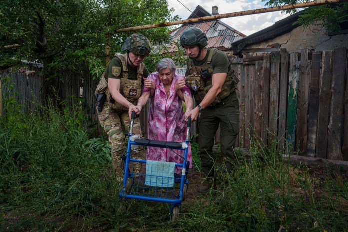 Agentes de la unidad de policía Ángeles Blancos ayudan a una mujer mayor a llegar a una camioneta durante una evacuación, en Toretsk, en la región ucraniana de Donetsk, el 28 de junio de 2024. (AP Foto/Evgeniy Maloletka)