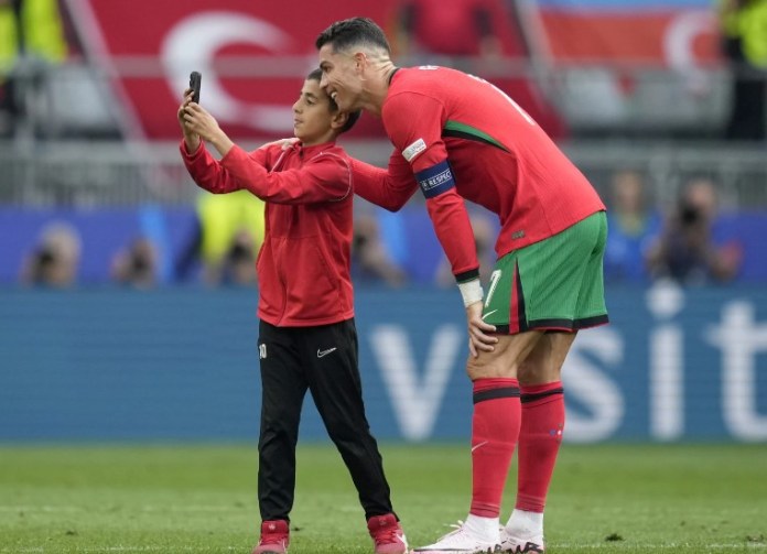 Un joven invasor del campo se toma una selfie con el portugués Cristiano Ronaldo durante un partido del Grupo F entre Turquía y Portugal en el torneo de fútbol Euro 2024 en Dortmund, Alemania, el sábado 22 de junio de 2024. (Foto AP/Themba Hadebe)