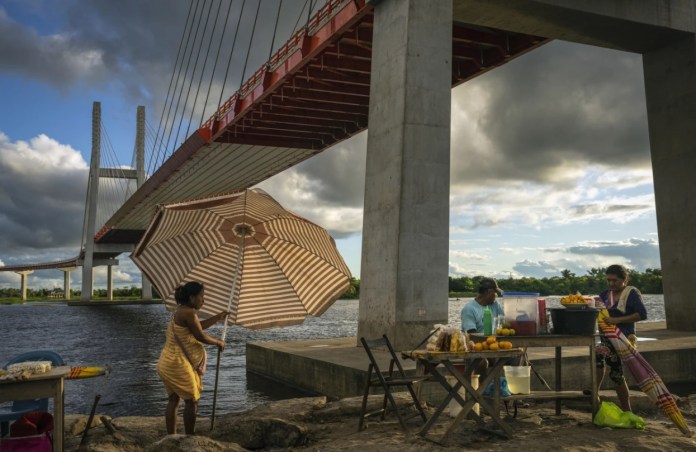 Los vendedores instalan puestos de comida debajo de un puente que forma parte de un proyecto de carretera federal que se extiende sobre el río Nanay, en Iquitos, Perú, el 27 de mayo de 2024. (Foto AP/Rodrigo Abd)