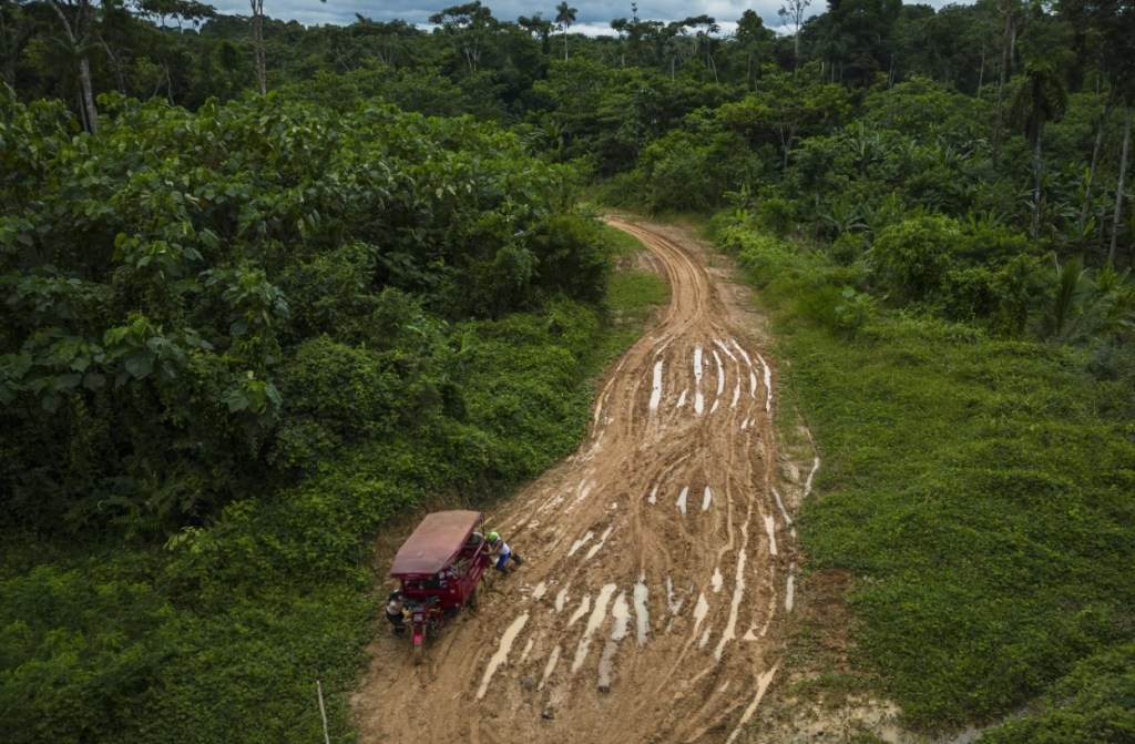 Muruis empuja un triciclo de carga atrapado en el barro en el camino propuesto para una carretera federal que se construirá desde Iquitos hasta el distrito de El Estrecho, Centro Arenal, Perú, el 28 de mayo de 2024. (Foto AP/Rodrigo Abd)