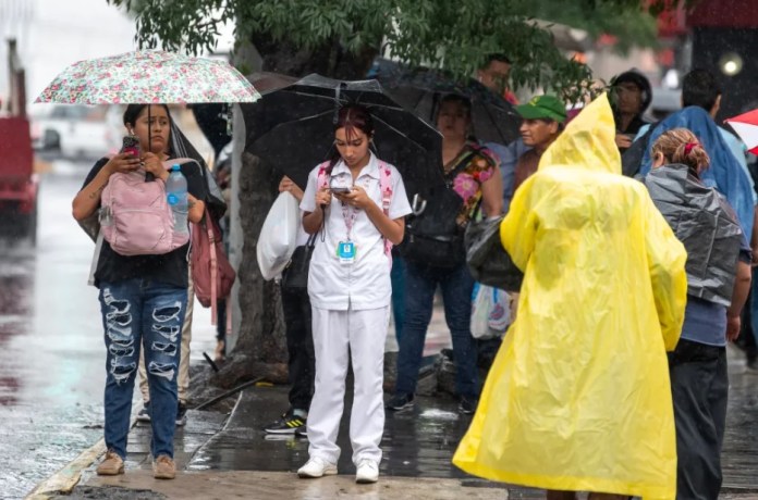 Ciudadanos caminan con paraguas e impermeables bajo una lluvia provocada por Alberto, en Monterrey (México). EFE/Miguel Sierra.