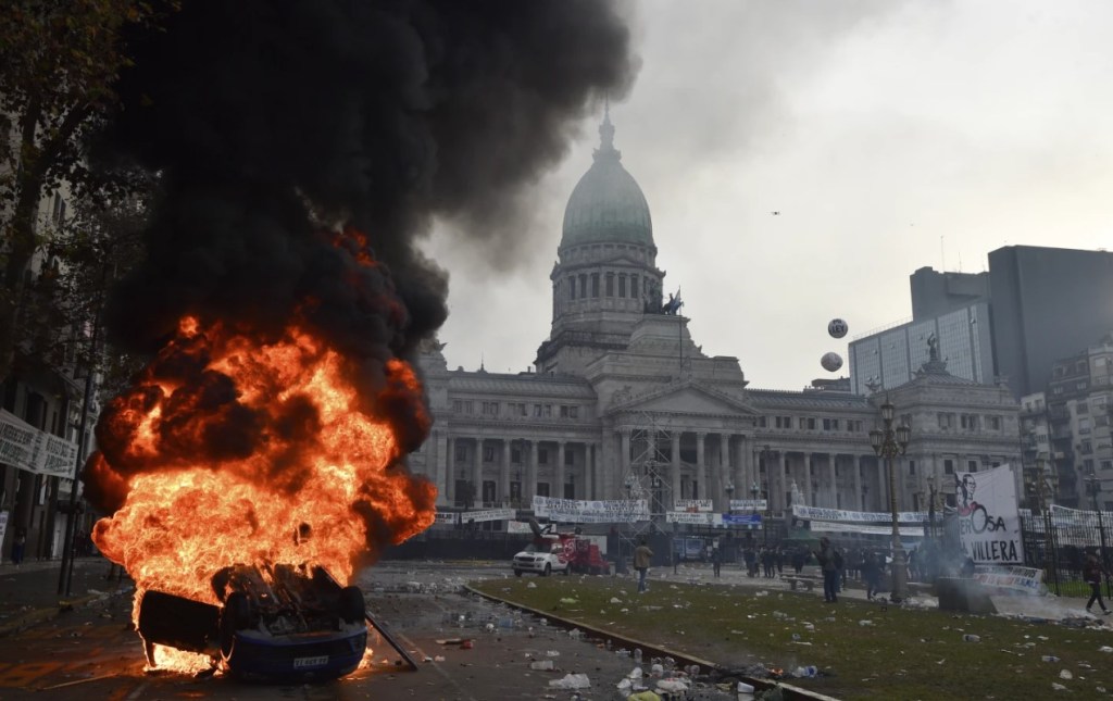 Un automóvil arde durante enfrentamientos entre la policia y manifestantes antigubernamentales frente al congreso. Foto AP / Gustavo Garello