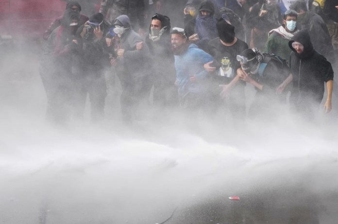 Manifestantes antigubernamentales son rociados por un cañón de agua de la policía frente al Congreso mientras los legisladores debaten un proyecto de ley de reforma promovido por el presidente argentino Javier Milei en Buenos Aires, Argentina, el miércoles 12 de junio de 2024. (Foto AP/Natacha Pisarenko)