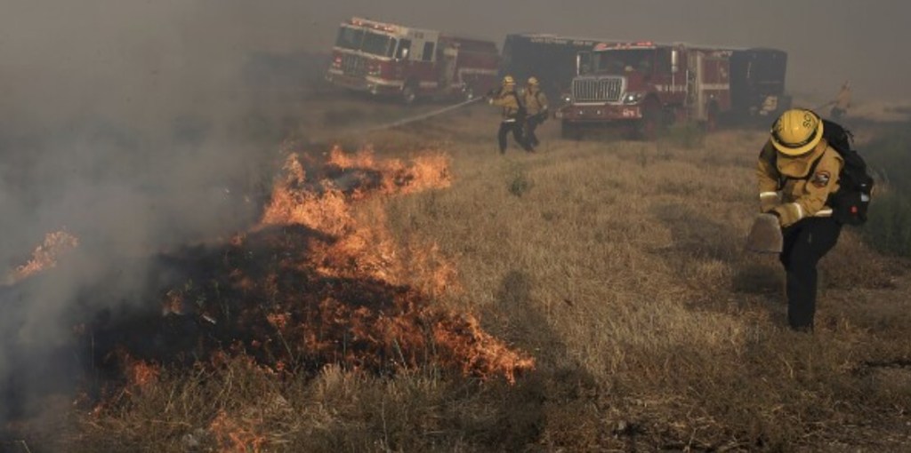 Un equipo de Santa Clara Cal Fire lucha por extinguir un incendio puntual en la mediana de la Interestatal 580, durante el incendio Corral al oeste de Tracy, California, el sábado 1 de junio de 2024. (Kent Porter/The Press Democrat vía AP)