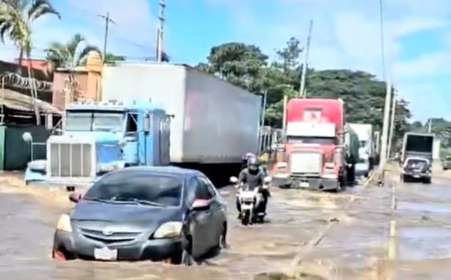 Los vehículos intentan transitar la carretera inundada. (Foto: captura de video)