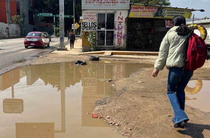 Personas caminan entre agua estancada en una calle, este viernes en Oaxaca (México). EFE/Jesús Méndez