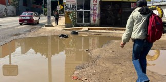 Personas caminan entre agua estancada en una calle, este viernes en Oaxaca (México). EFE/Jesús Méndez