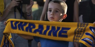 Mikhail, de 5 años, sostiene una bufanda con la inscripción "Ucrania" durante una proyección pública del partido de la Eurocopa 2024 entre Ucrania y Bélgica en Kiev, Ucrania, el miércoles 26 de junio de 2024. (Foto AP/Alex Babenko)