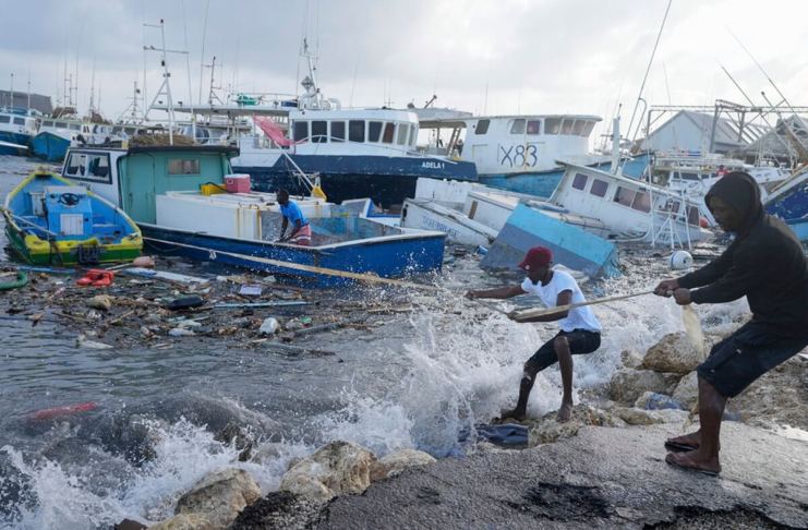 Pescadores arrastran un barco dañado por el paso del huracán Beryl para amarrarlo a puerto, en Bridgetown, Barbados, el 1 de julio de 2024. (AP Foto/Ricardo Mazalán)