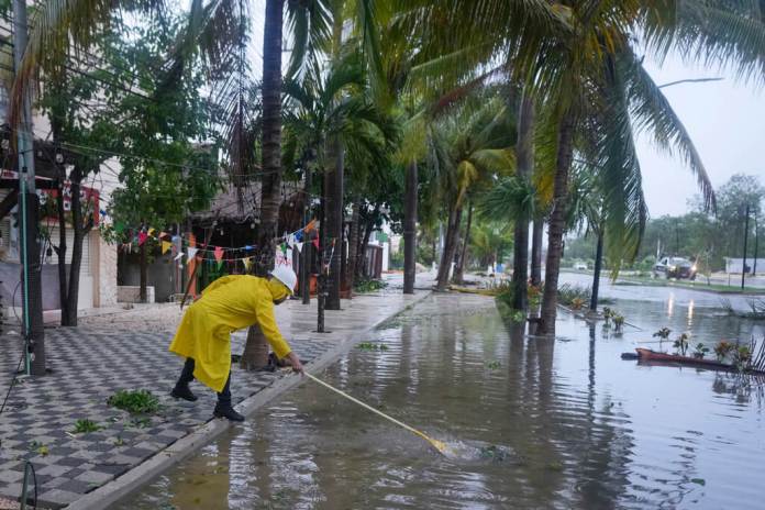 Un hombre limpia un desagüe después del paso del huracán Beryl. (AP Foto/Fernando Llano)