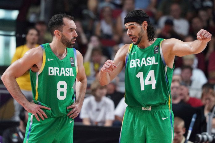 Vitor Benite (izquierda) y Leo Meindil, de Brasil conversan durante el partido clasificatorio al baloncesto de los Juegos Olímpicos entre Letonia y Brasil, en Riga, Letonia, el domingo 7 de julio de 2024. (AP Foto/Roman Koksarov)